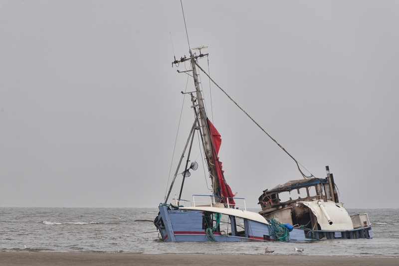 A sinking abandoned ship at the seashore under the clear sky