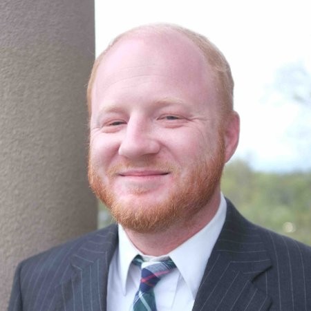 Headshot of Alabama Personal Injury Attorney Andrew Schwartz, smiling in a pinstripe suit and plaid tie outdoors.